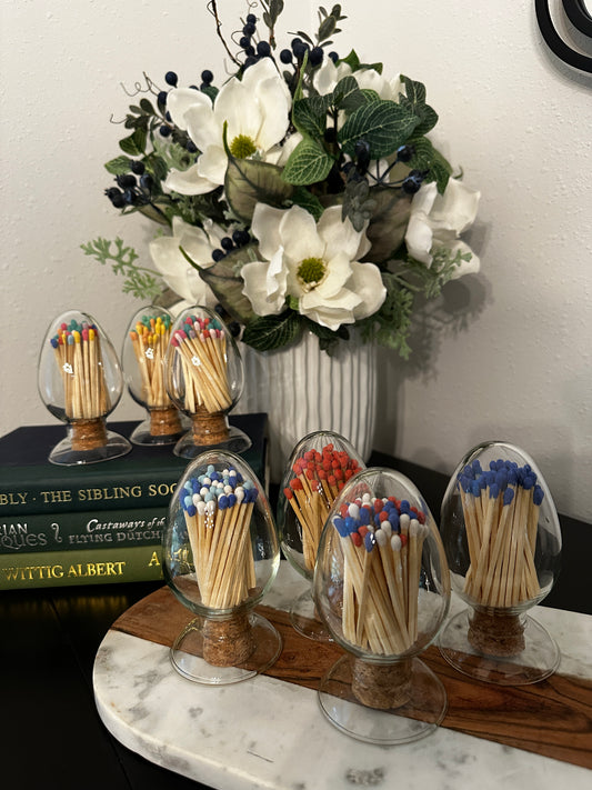 Matchsticks in glass containers with decorative flowers on a surface